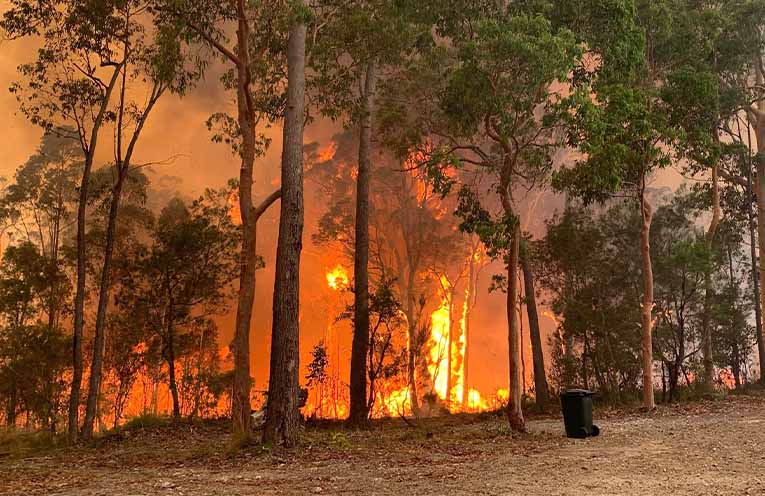 Firefighter dies as communities stay on high fire alert