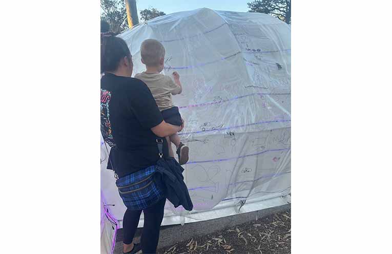 Locals getting the chance to write on the huge jacaranda flower, created by Stevi and Peter from Redbarn Studio. Photo: Althea Guinsberg.
