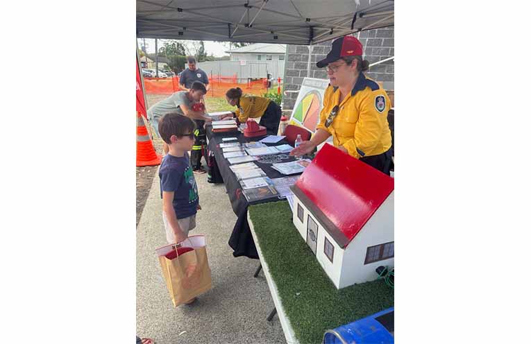 Brigade volunteer Natasha Jakubaszek chatting with a young local about what number to call in an emergency. Photo: Althea Guinsberg.